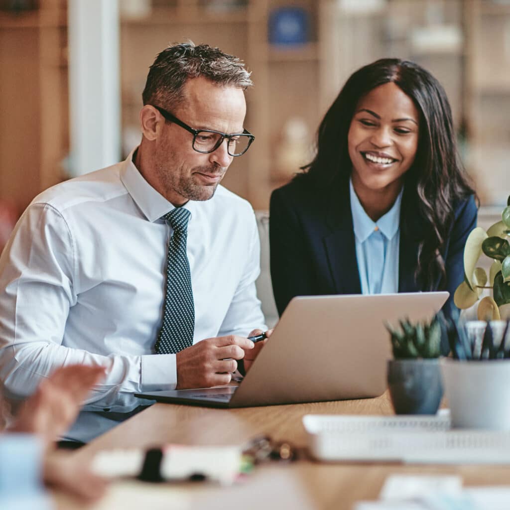 Two smiling diverse businesspeople using a laptop