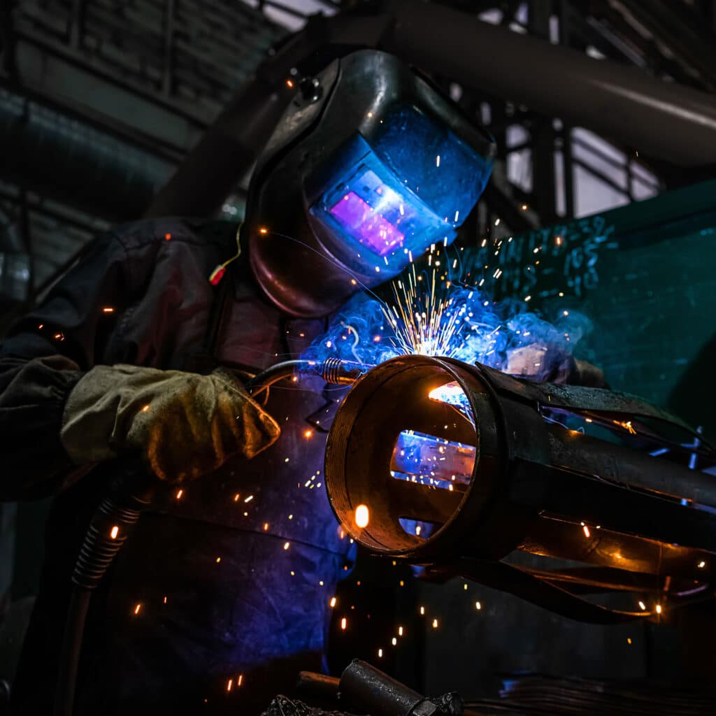 Welder in protective helmet welding metal