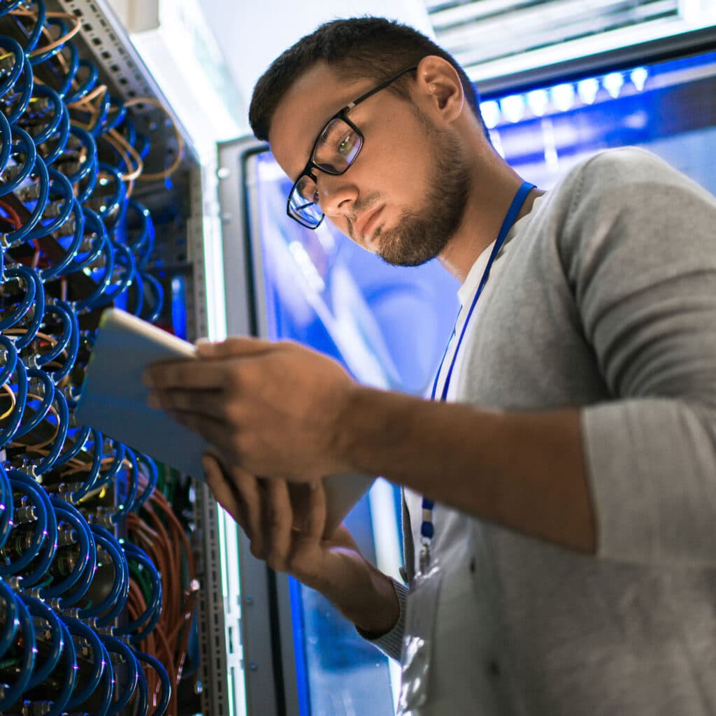 Man using digital tablet standing by server cabinet
